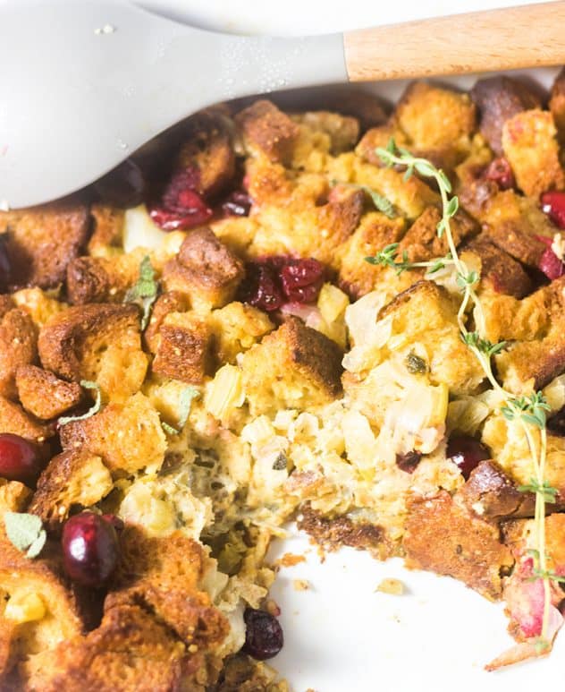 Gluten Free Cranberry Stuffing in a casserole dish garnished with fresh thyme.