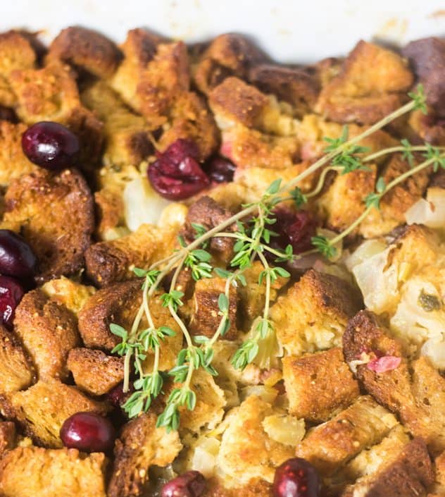 Gluten Free Cranberry Stuffing in a casserole dish and garnished with fresh thyme.