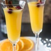 Mimosa in champagne glass with cinnamon sticks & cranberries