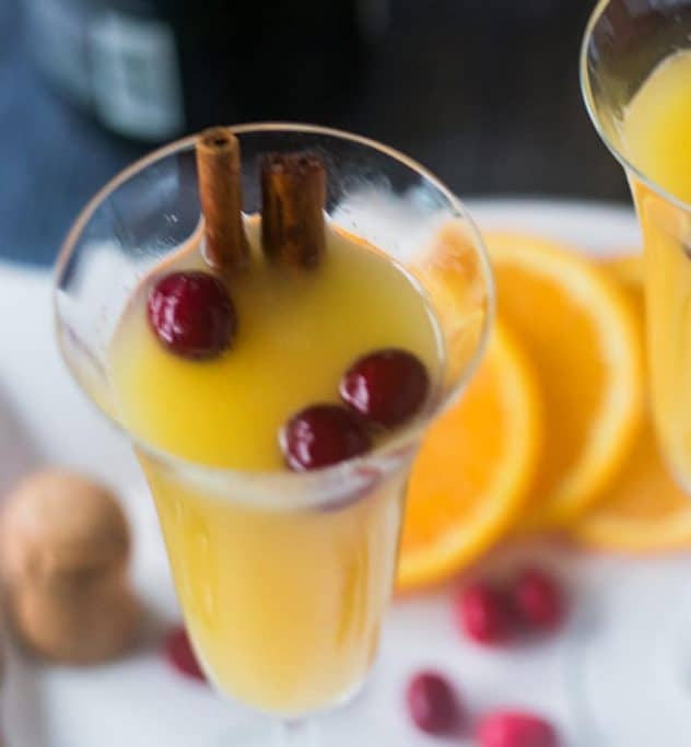 Mimosa in a champagne glass with cranberries & cinnamon sticks