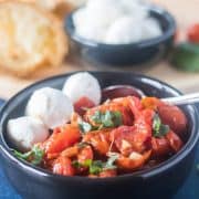 Caprese in a black bowl with a spoon.