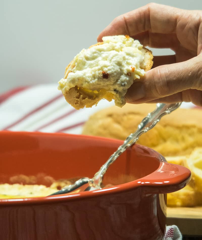 Baked Ricotta Cheese that is spread on a slice of a baguette.