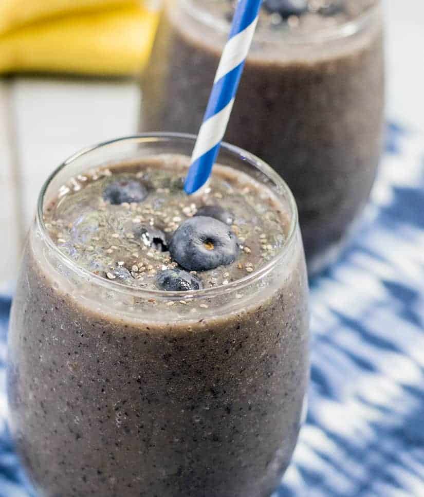 Blueberry Banana Smoothie in a clear glass with a blue and white straw