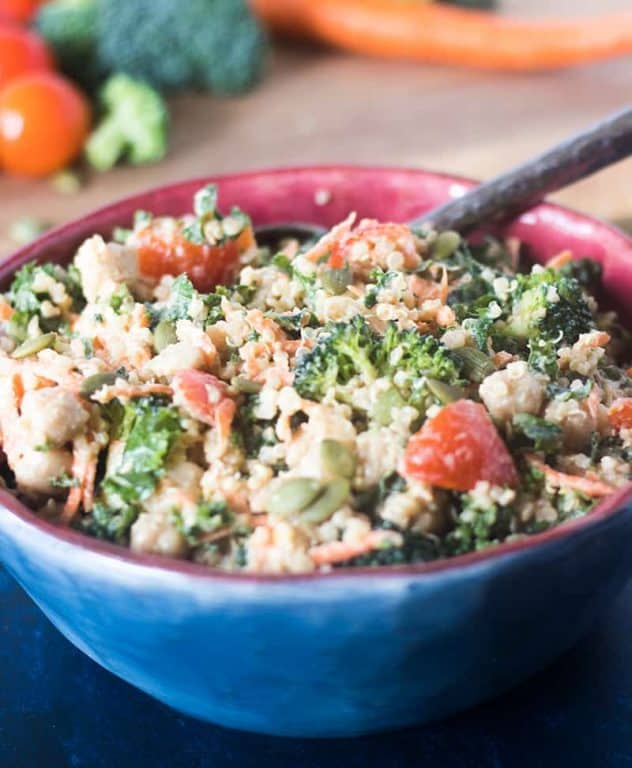 kale, quinoa, broccoli, carrots, chickpeas, cherry tomatoes in a bowl tossed with tahini dressing