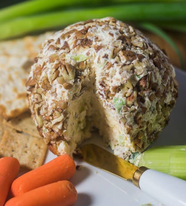 Cheese Ball on plate with knife and carrots that has been sliced.