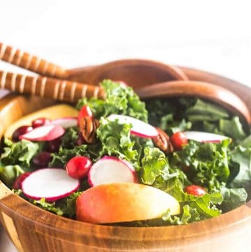 Apple Cranberry Kale Salad in wooden salad b.owl with serving spoons