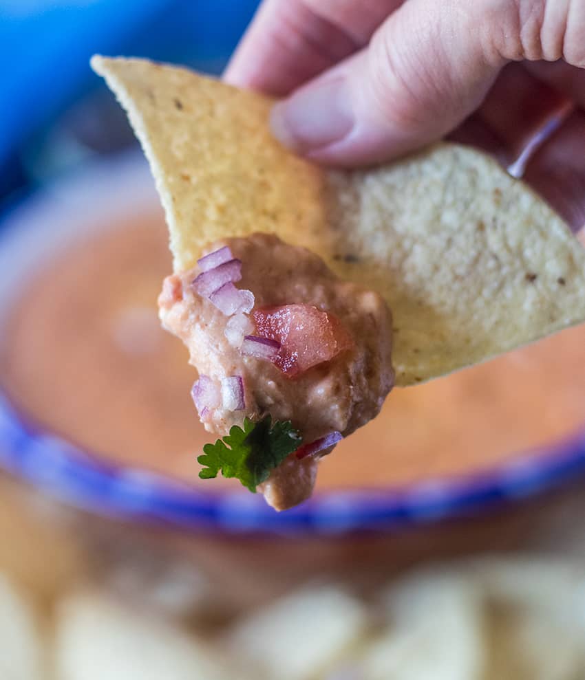 Bean Dip on a tortilla chip being held in hand.
