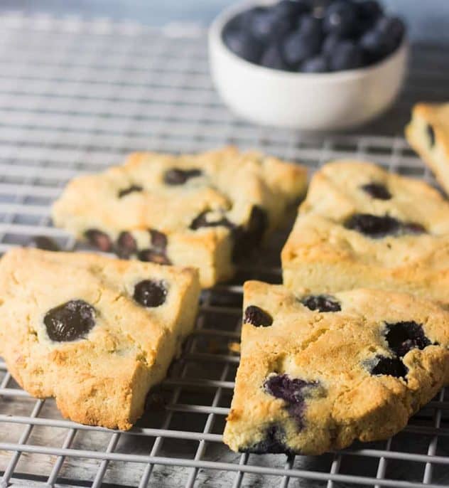 Blueberry Scones on a cooling rack with a bowl of blueberries