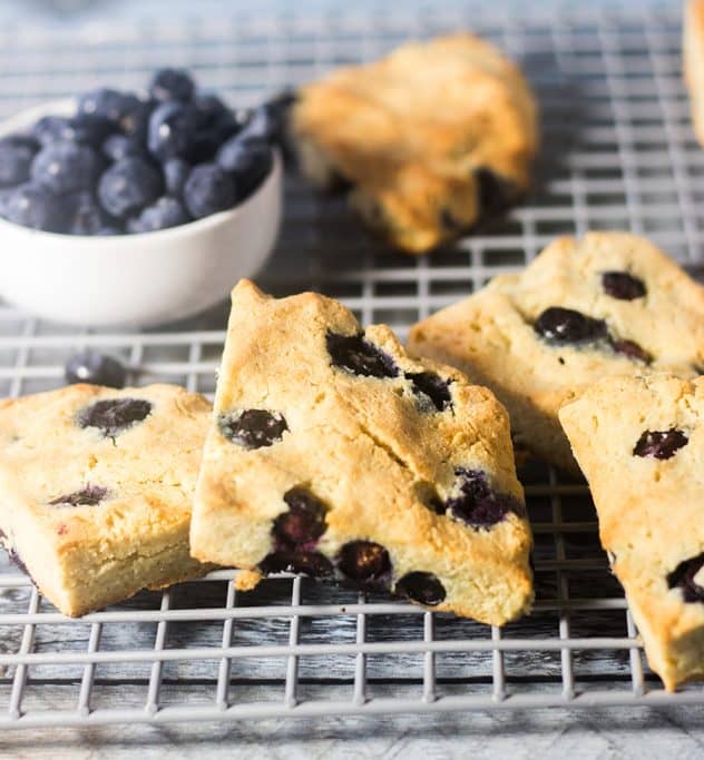 Blueberry Scones on a cooling rack and bowl of blueberries.