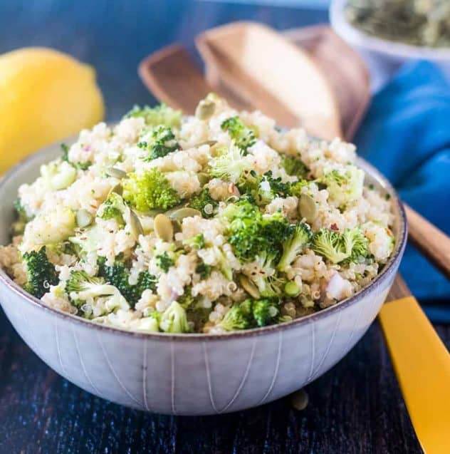 Broccoli Quinoa Salad in a bowl with some wooden salad spoons and a lemon.