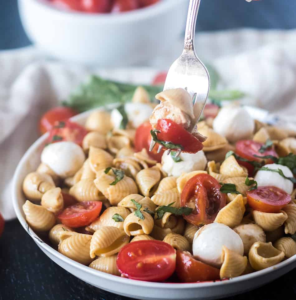 Caprese Pasta Salad in a white bowl and some on a fork.