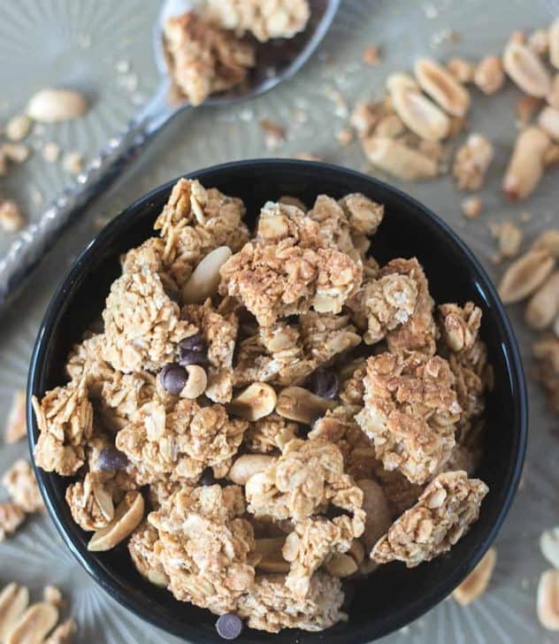 Peanut Butter Granola Clusters in a black bowl with a spoon beside it.