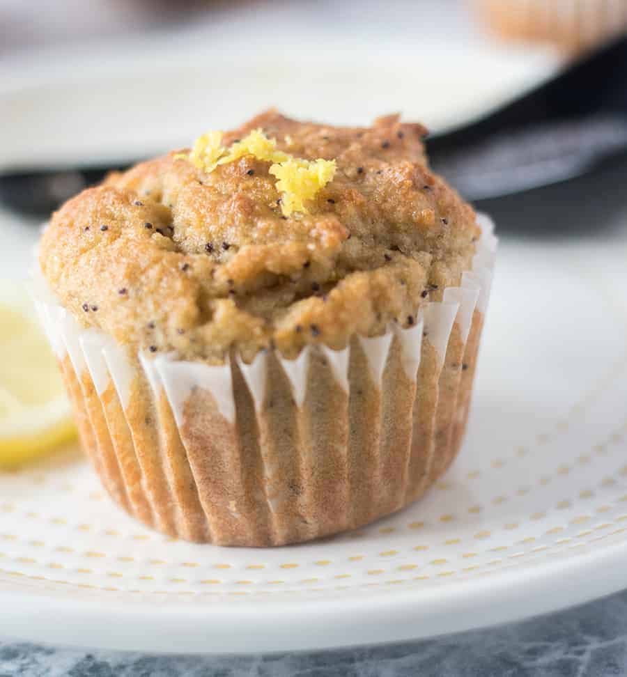 Lemon Poppy Seed Muffin on a white plate with yellow trim and topped with fresh lemon zest.