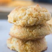 Three Cheddar Biscuits stacked on top of each other on a baking pan lined with parchment paper.