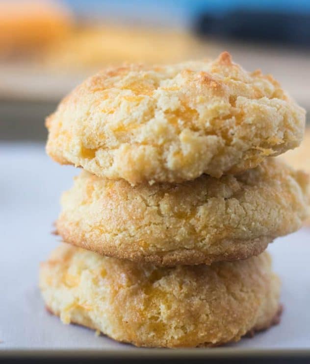 Three Cheddar Biscuits stacked on top of each other on a baking pan lined with parchment paper.