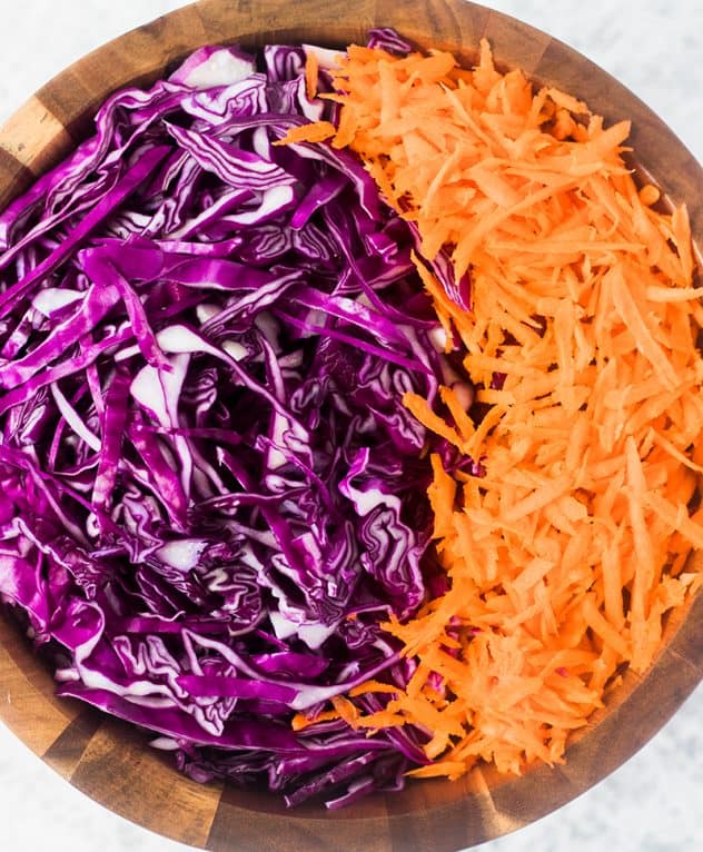 Shredded red cabbage and carrots in a wooden salad bowl.