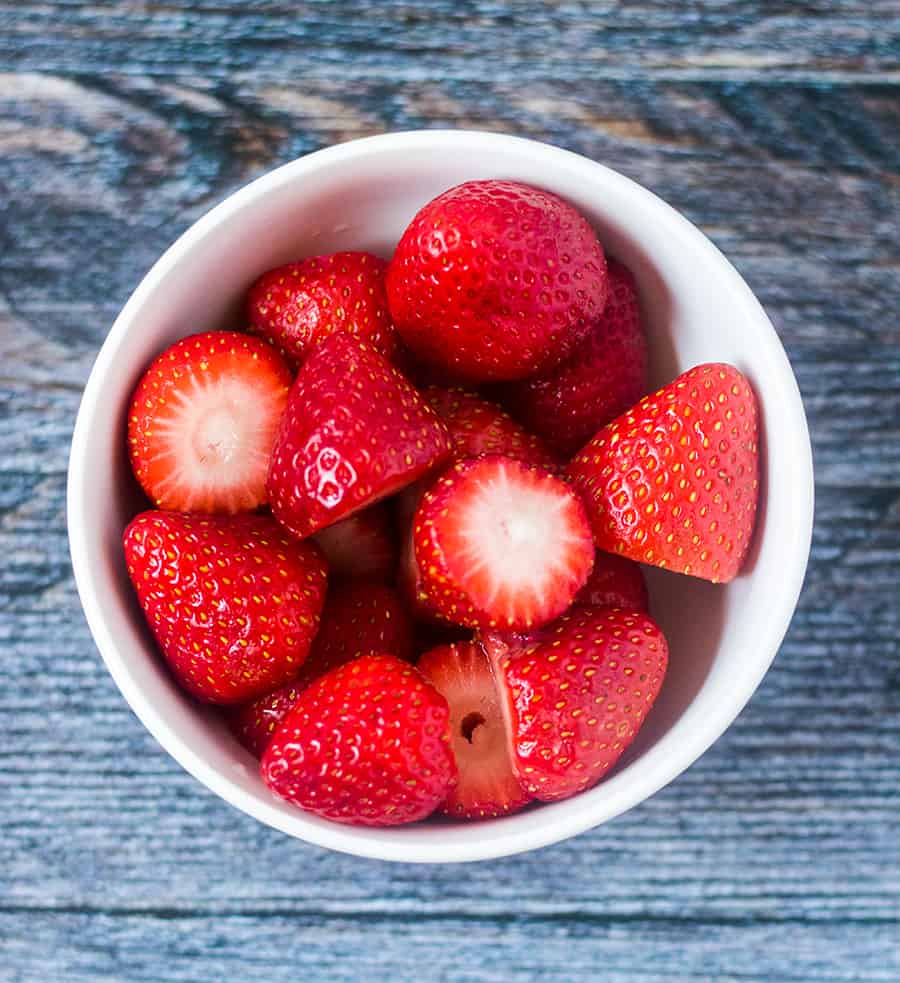 Fresh strawberries in a white bowl.