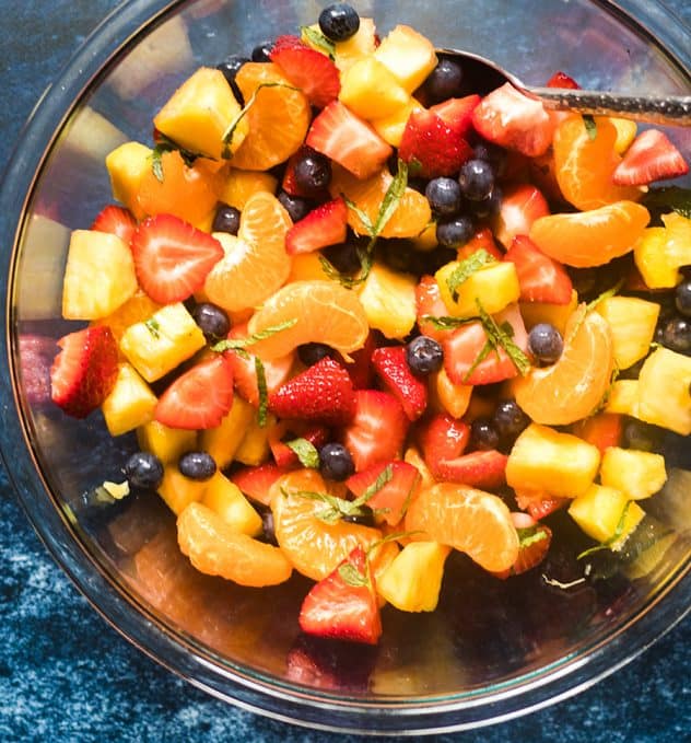 Fruit salad in a large glass serving bowl.