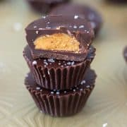 Dark Chocolate Cashew Nut Butter Cups stacked on top of each other with one cut in half.