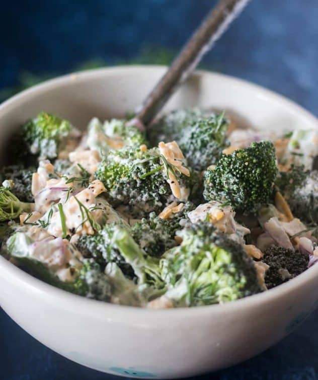 Broccoli Salad in a white bowl with a silver serving spoon.