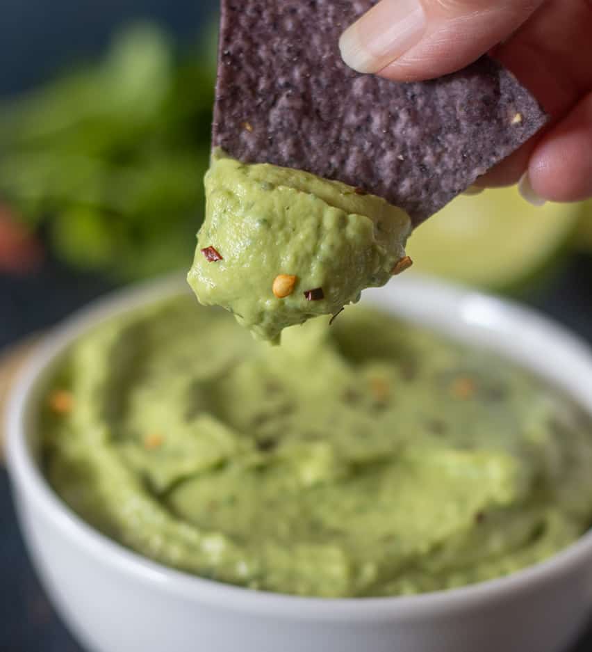 Avocado dip on a tortilla chip.