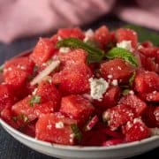Watermelon Feta Mint Salad in a white bowl garnished with fresh mint leaves.