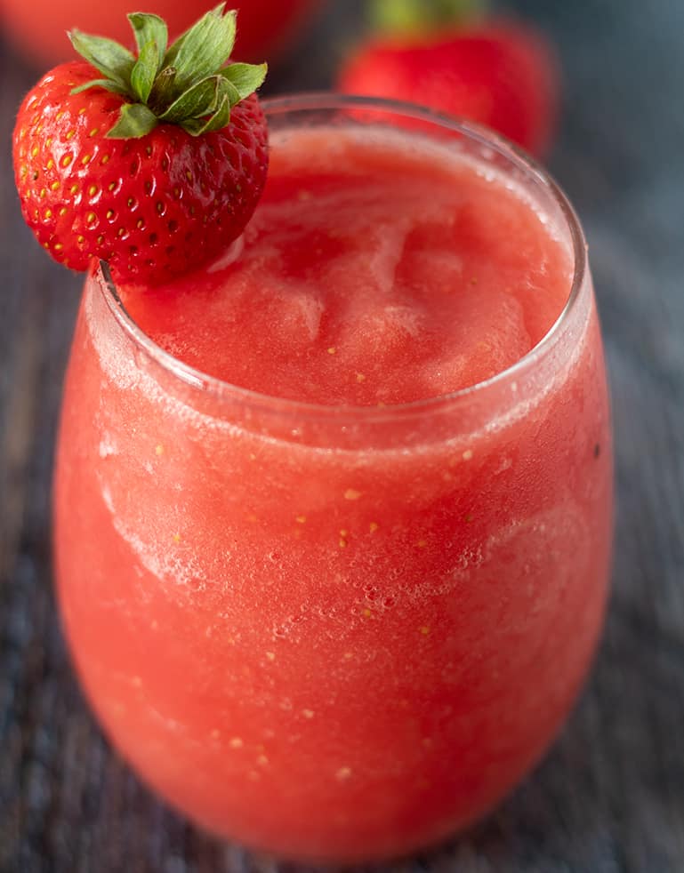 Watermelon Strawberry Wine Slushies in a glass garnished with a strawberry.