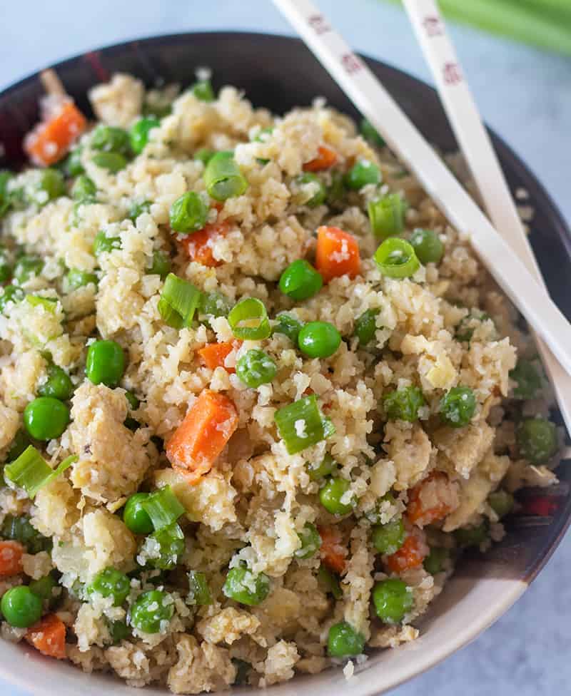 Cauliflower Fried Rice in a bowl with chopsticks for eating.