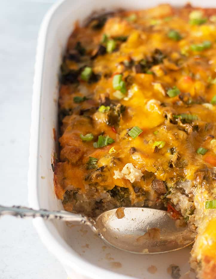 Tater Tot Breakfast casserole being served with silver spoon .