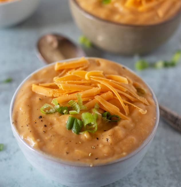 Potato soup topped with green onions and shredded cheddar cheese.