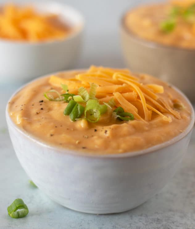 Slow Cooker Potato Soup topped with green onions and shredded cheddar cheese.
