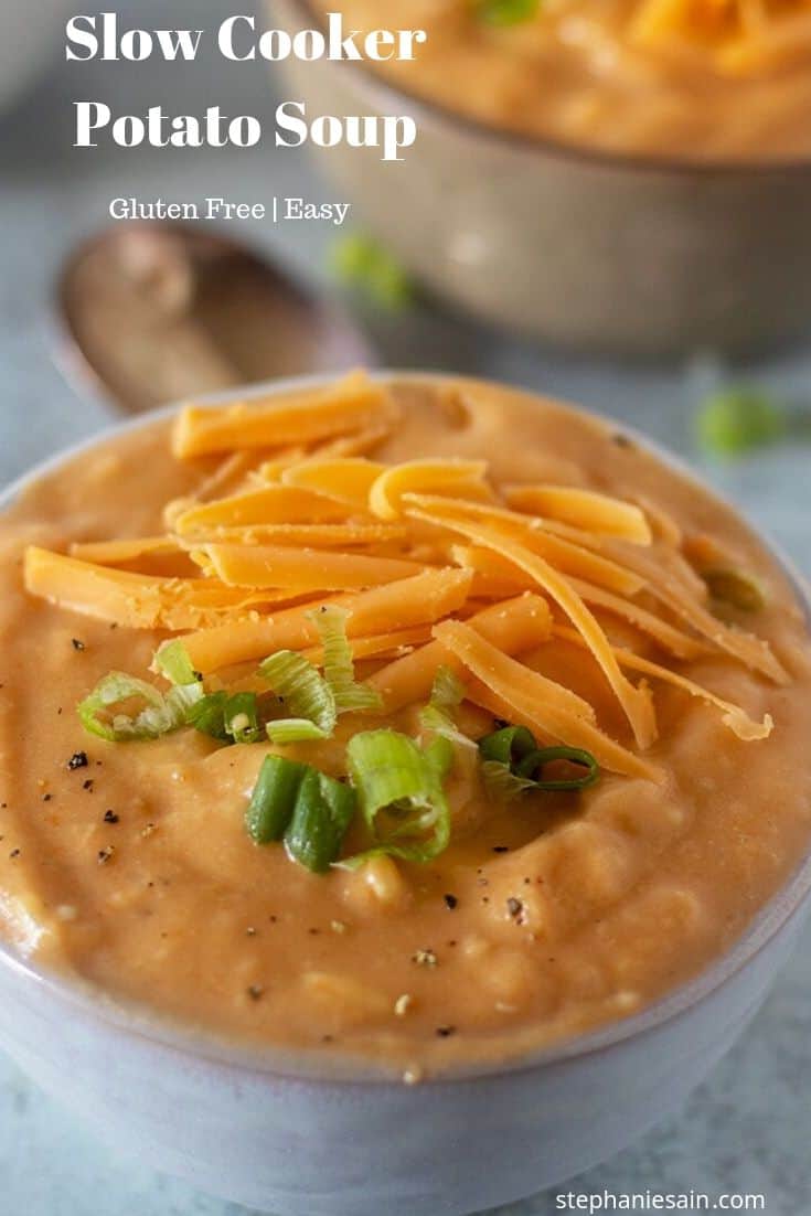 Slow Cooker Potato soup with green onions and shredded cheddar cheese.