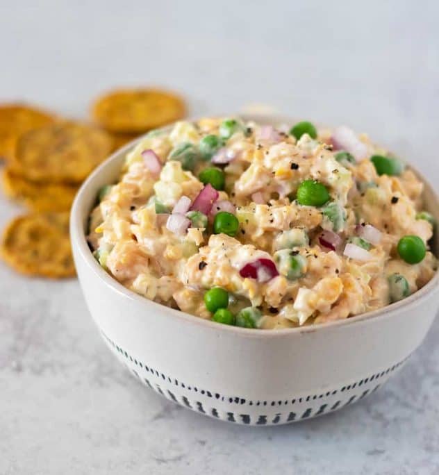 Chickpea salad in a bowl with crackers next to it.