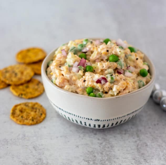 Chickpea salad in a white bowl with crackers for serving.