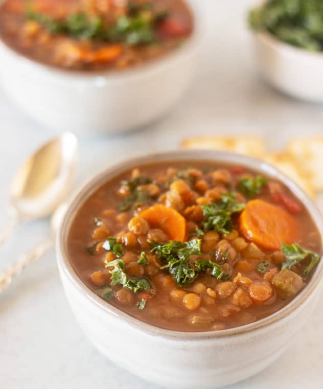 slow cooker lentil soup in a bowl topped with fresh chopped kale.
