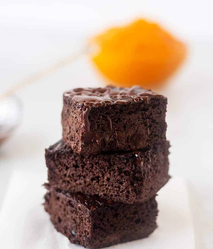 pumpkin brownies stacked with bowl of pumpkin in the background