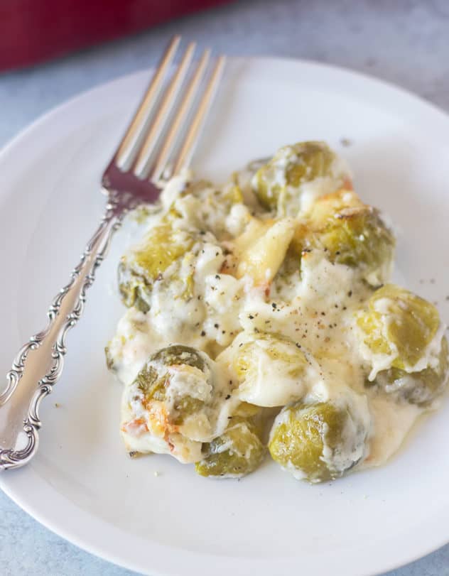 brussel sprouts au gratin on a white plate with a silver fork.