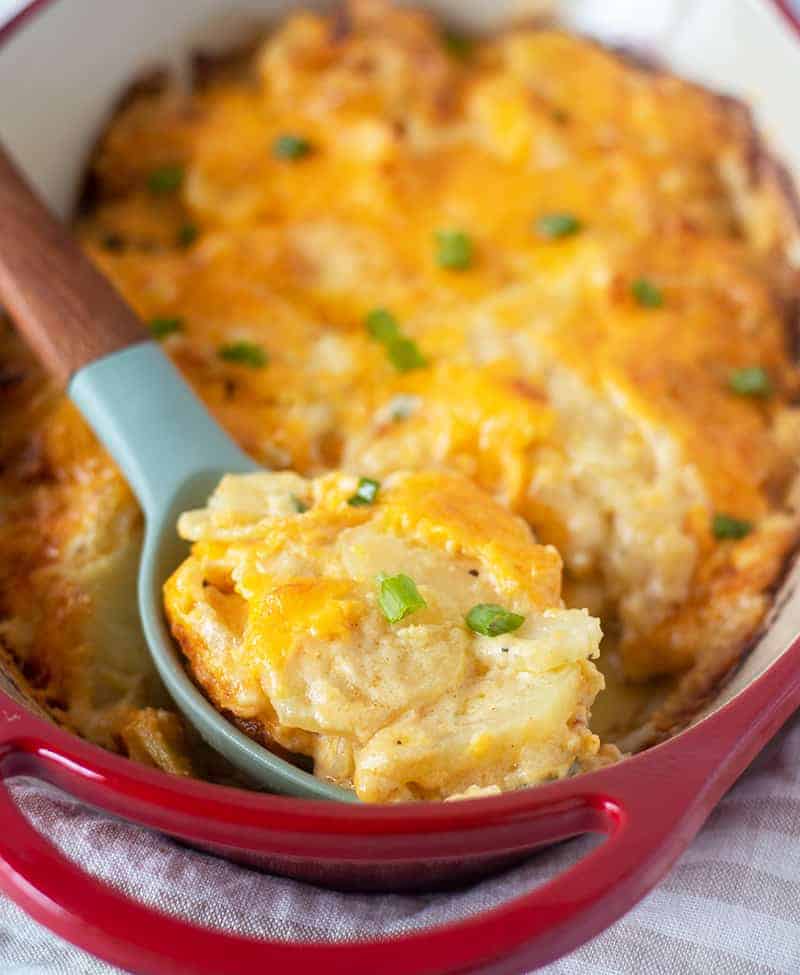 cheesy scalloped potatoes in a pan with a spoon