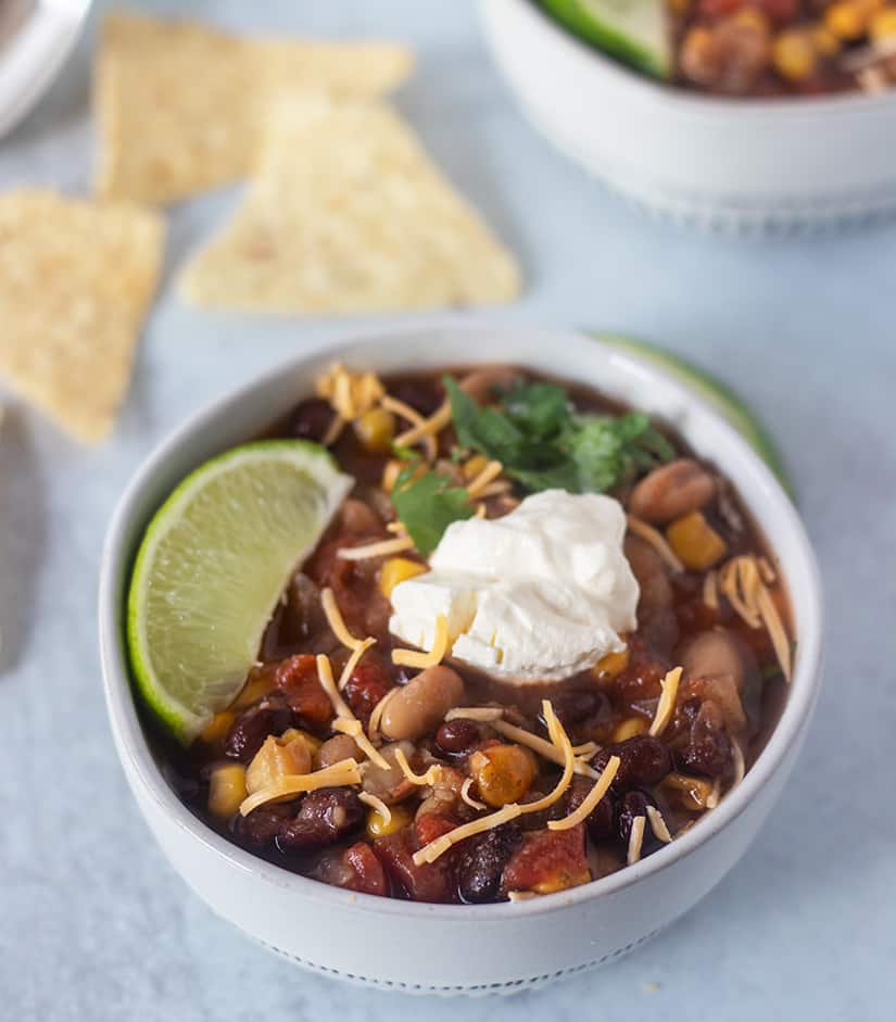 Slow Cooker Taco Soup in a bowl with a lemon wedge, cheese and sour cream.