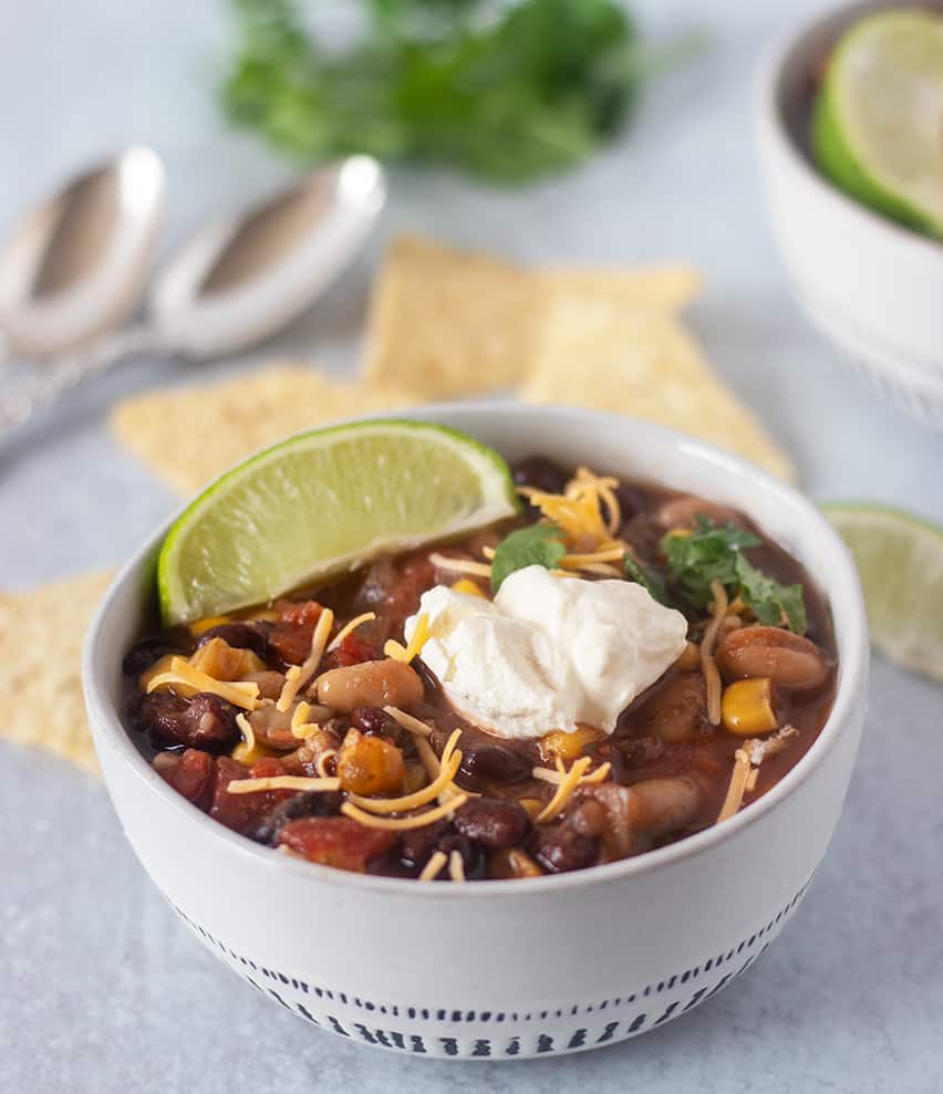 slow cooker taco soup served with tortilla chips, sour cream, cheese and a lime wedge