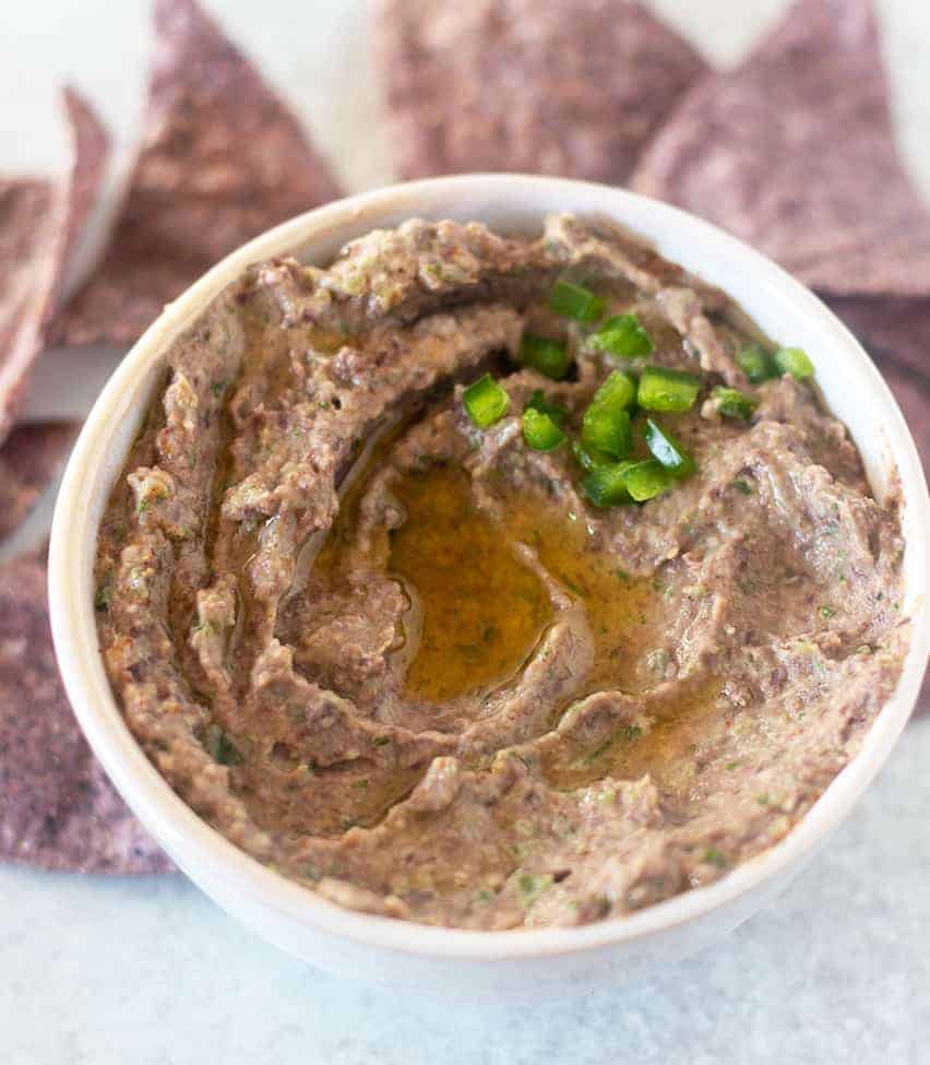 Black Bean Hummus in a white bowl topped with olive oil and jalapeños
