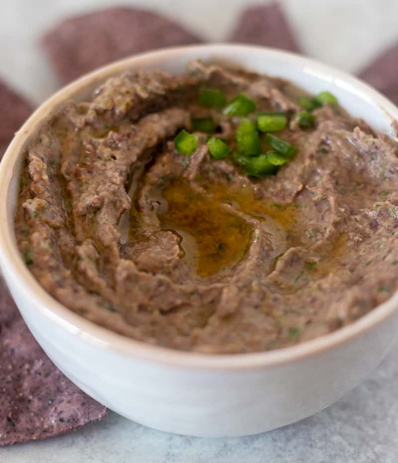 Black Bean Hummus in a bowl drizzled with olive oil and diced jalapeños