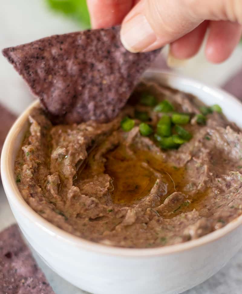 Black Bean hummus being dipped with a tortilla chip