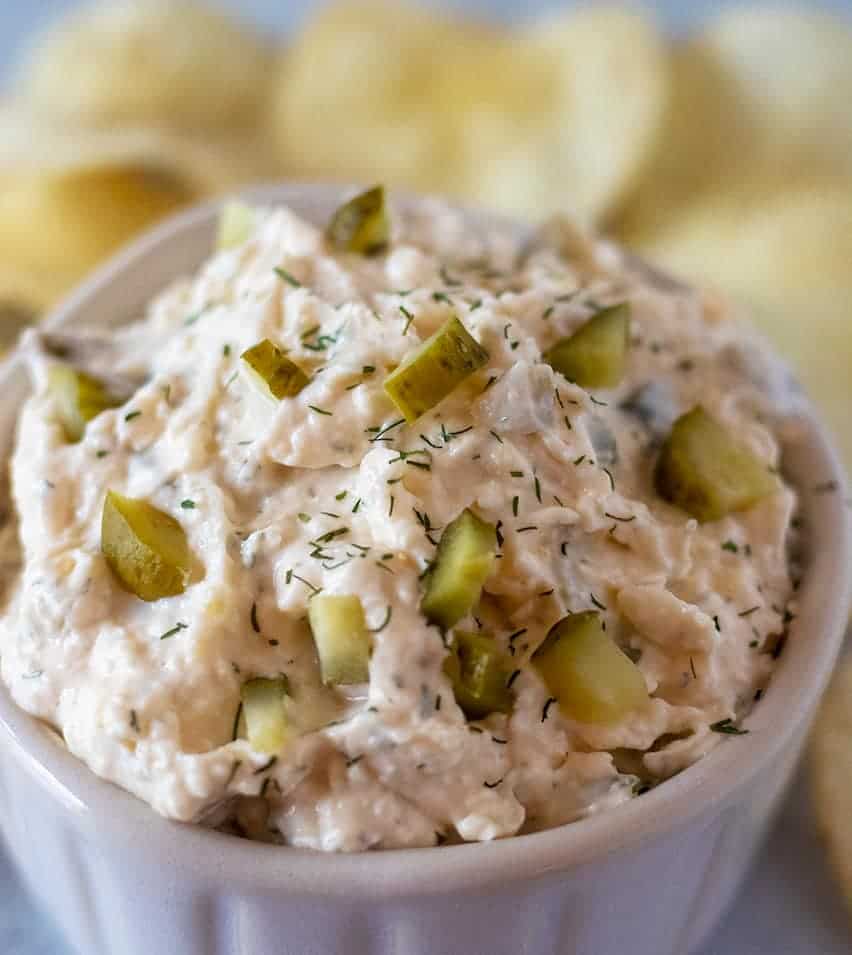 dill pickle dip in a bowl with some chips
