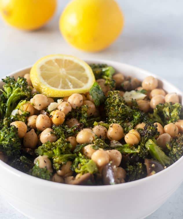 Broccoli Chickpea Salad in a bowl garnished with lemon wedge and lemons in background.