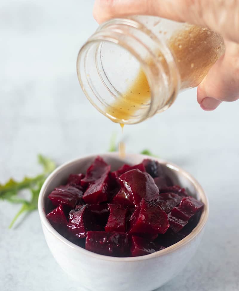 cubed beets being drizzled with viniagrette