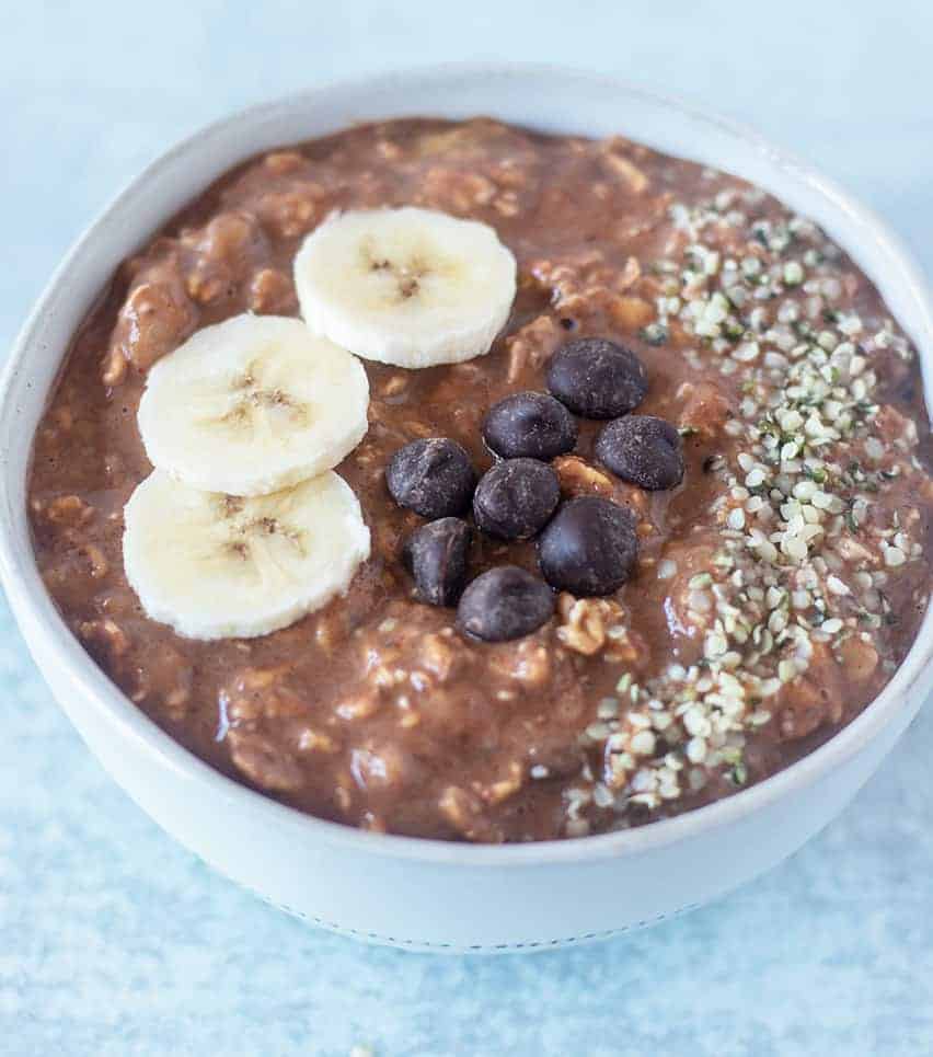 Chocolate Overnight Oats topped with banana slices, dark chocolate chips, and hemp seeds.