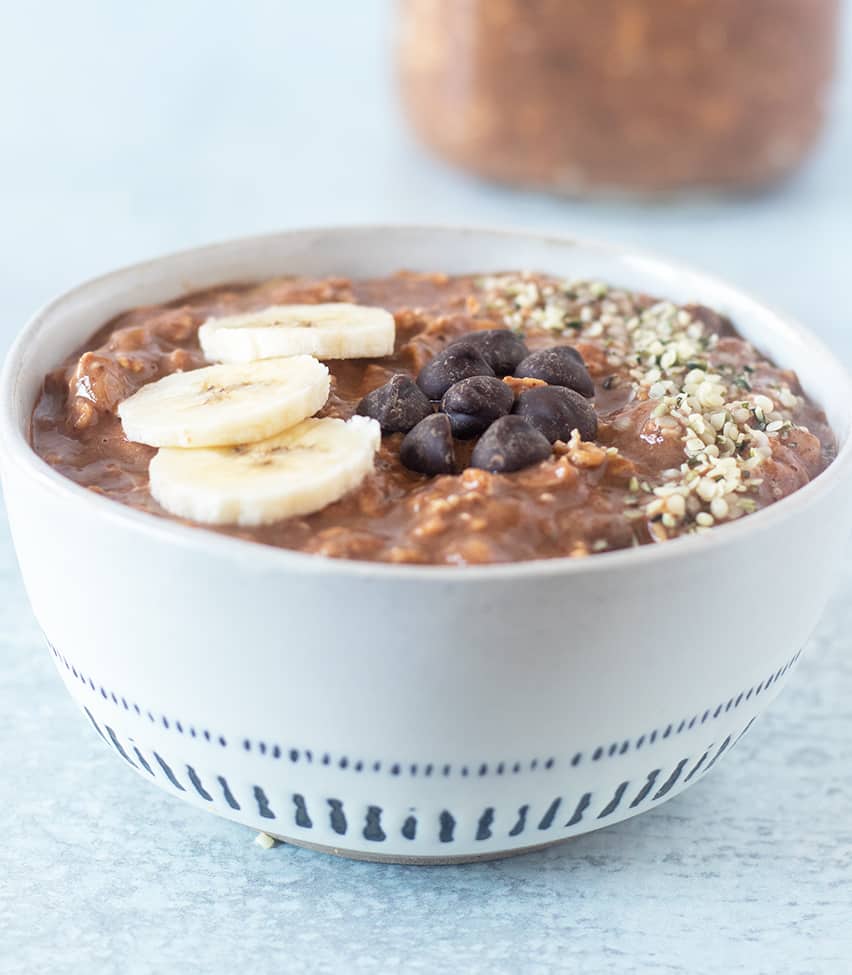 Chocolate Overnight Oats topped with bananas, dark chocolate chips and hemp seeds.