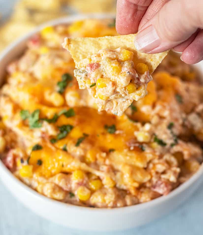 mexican corn dip being scooped up with a tortilla chip