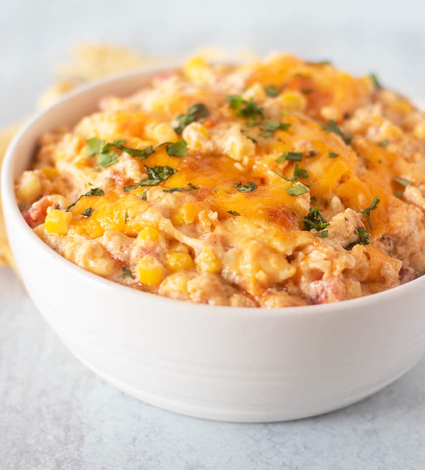 mexican corn dip in a white bowl garnished with cilantro